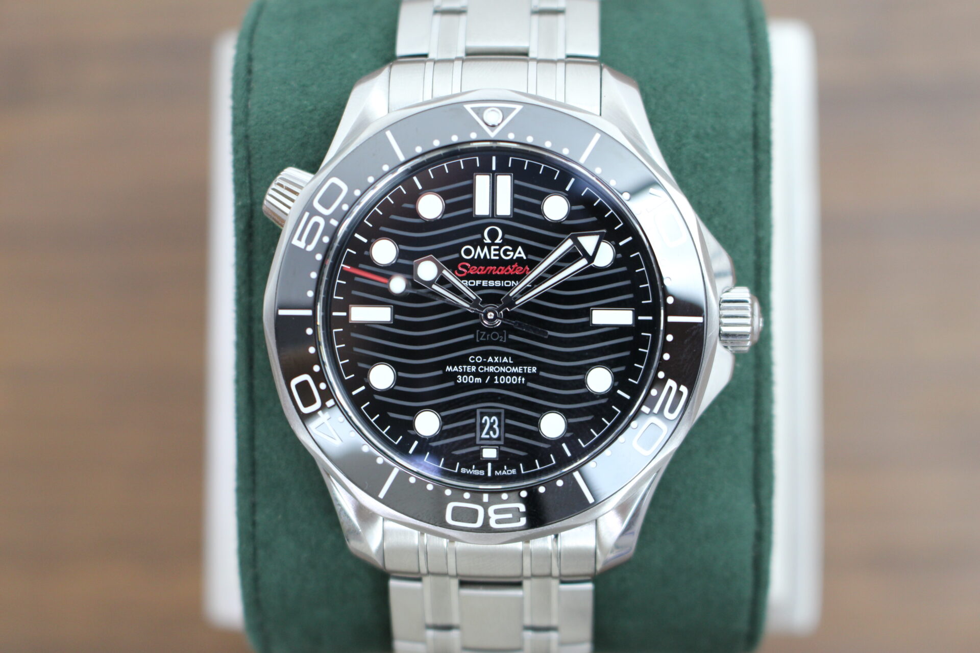 Omega Seamaster Diver Black 300m in it's box with swing tag, booklet and warranty cards on a green cushion