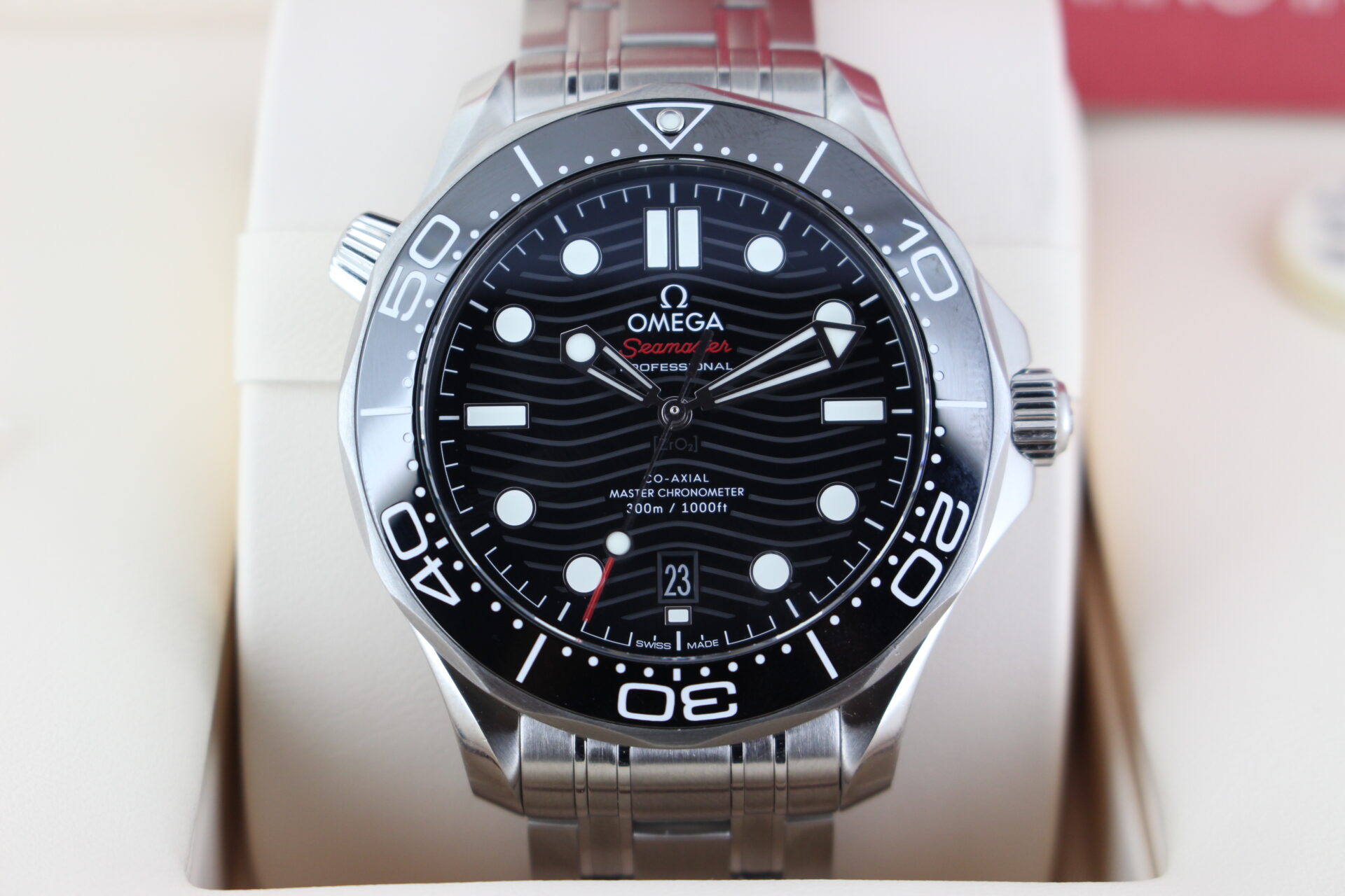 Close up of Omega Seamaster Diver Black 300m in it's box with swing tag, booklet and warranty cards
