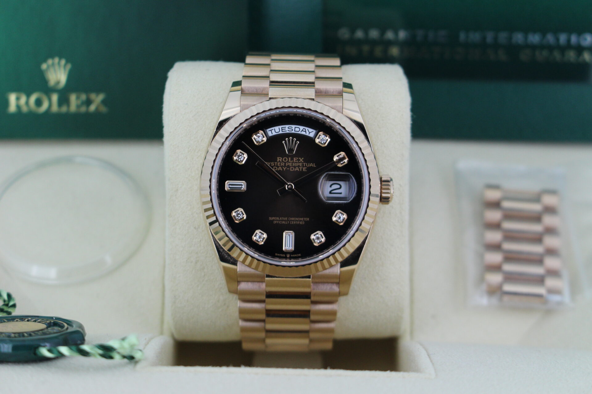 Rolex Day Date Chocolate Dial 128235 close up of the watch in it's box with links, swing tags, bezel protector, booklets and warranty card