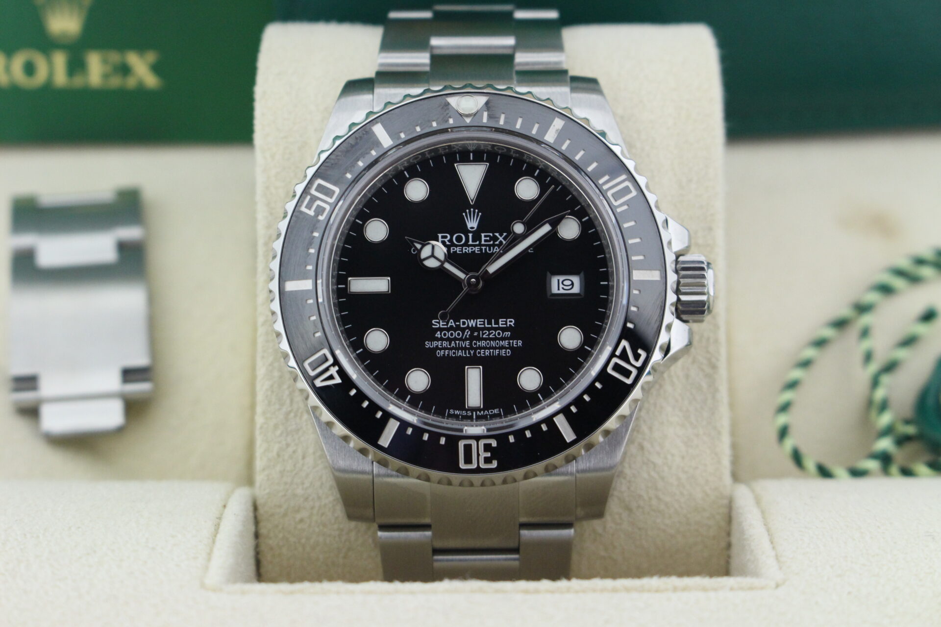 Close up of Rolex Sea-Dweller 116600 in it's box with green swing tag, booklet and warranty card