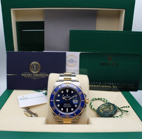 A Rolex Submariner Bluesy on display in its box with all accessories, warranty card and booklets alongside the original purchase receipt