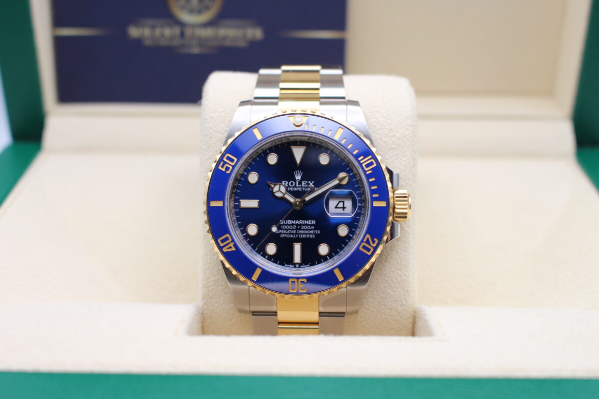 A Rolex Submariner 126613LB in a open Rolex box with Solent Timepieces logo behind it