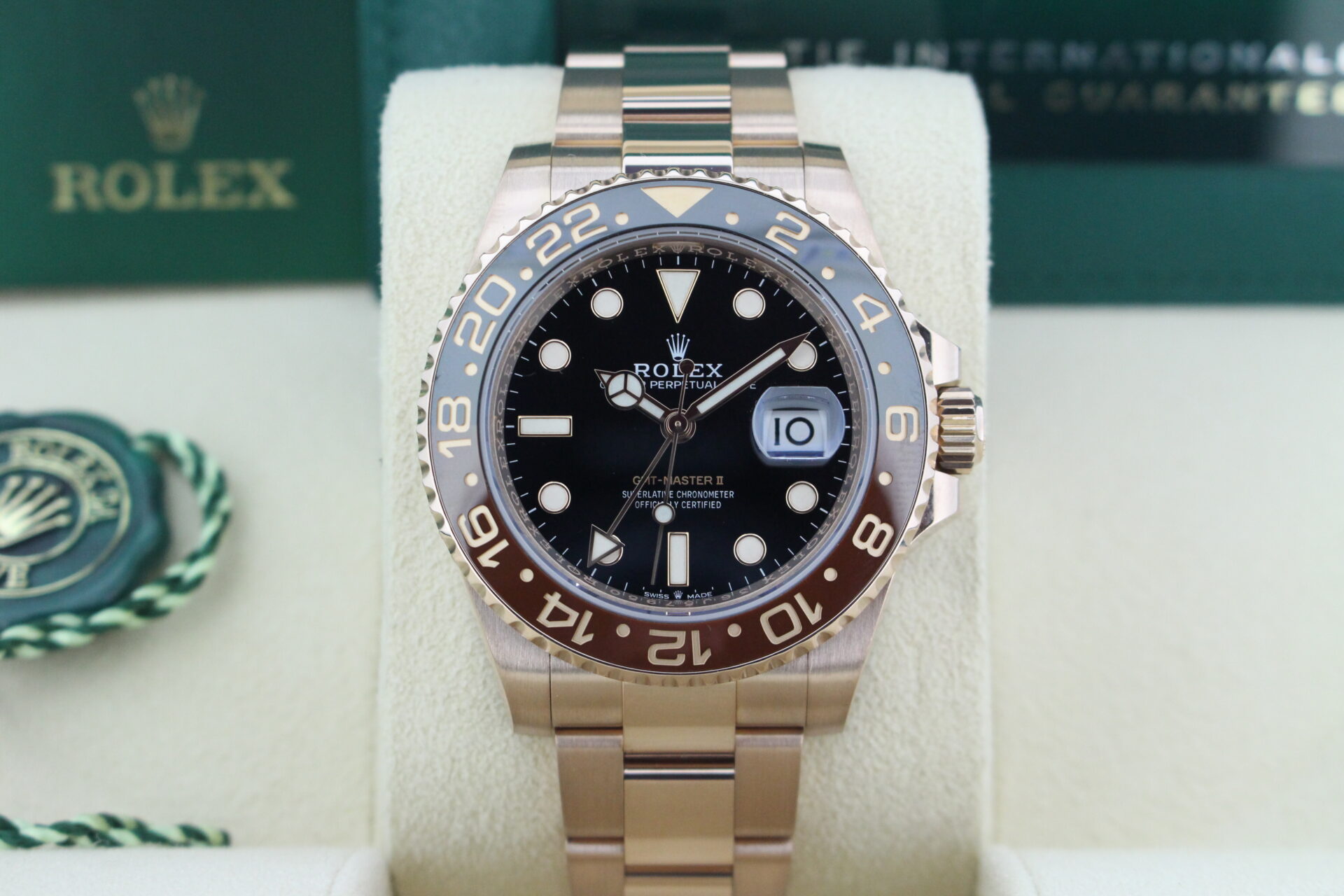 Close up of Rolex GMT Master II Full Everose Rootbeer 126715CHNR in it's box with green swing tag, booklet and warranty card