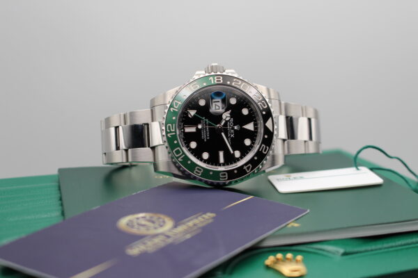 Rolex GMT Sprite on top of its green wave box with manual, swing tag and Solent Timepieces card in a lifestyle image