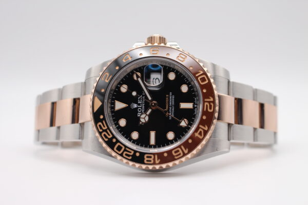 A Rolex GMT Master 2 Rootbeer on a white back ground. Watch laid on its side crown facing up