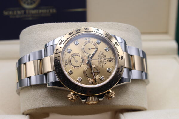 Rolex bi-metal daytona laid on its side on a watch cushion. Diamonds shining in the light