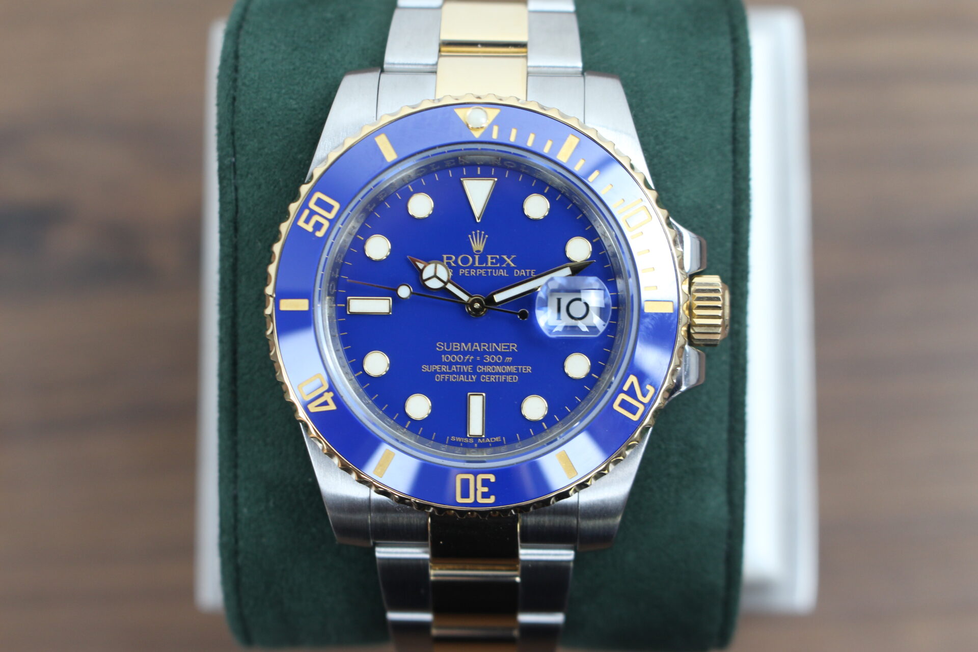 Rolex Submariner Bluesy 40mm 116613LB in it's box with red swing tags, booklets and warranty card on a green cushion